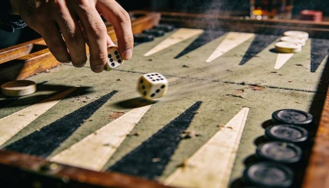 Hand Rolling Dice on Worn Backgammon Board with Smoky Amber Lighting and Wooden Table