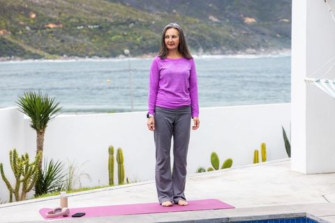 Woman practicing yoga on poolside mat overlooking coastal bay