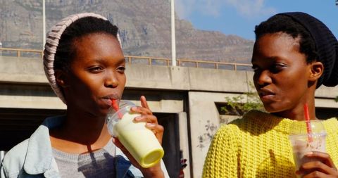 Twin Sisters Enjoying Smoothies Outdoors