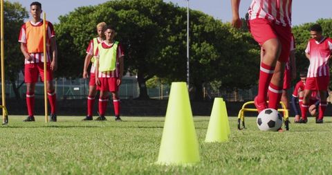 Soccer Player Dribbling Through Cones on Field in Full Gear