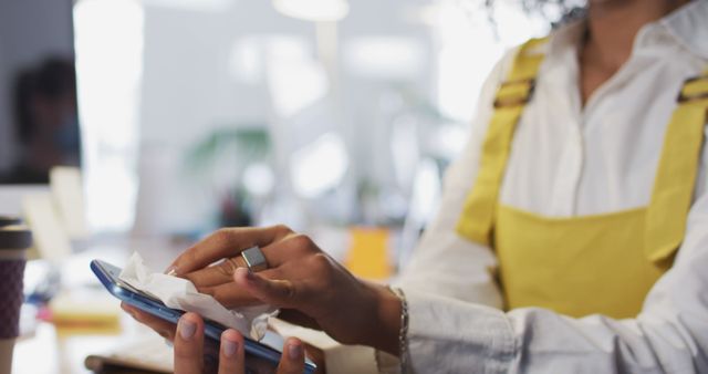 Woman Cleaning Smartphone Screen with Tissue in Office - Download Free Stock Images Pikwizard.com