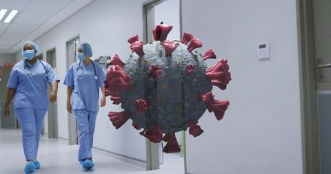 Nurses walking past oversized coronavirus model in hospital corridor