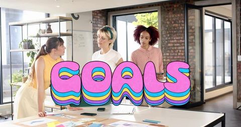 Creative team brainstorming and collaborating with colorful goals graphic in open plan studio