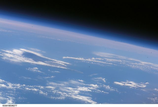 This captures a stunning view from the International Space Station, showcasing Earth's horizon with a bluish glow and scattered clouds. The Hawaiian Islands can barely be distinguished far below. Ideal for educational content relating to space, atmospheric studies, or geography. Also suitable for science and technology publications focusing on Earth observations, astronomy, and space exploration.