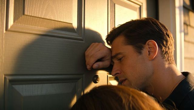 Man listening through door peephole at golden hour front door closeup