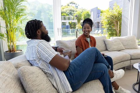 Sunlit living room conversation featuring african american couple relaxing on sectional sofa