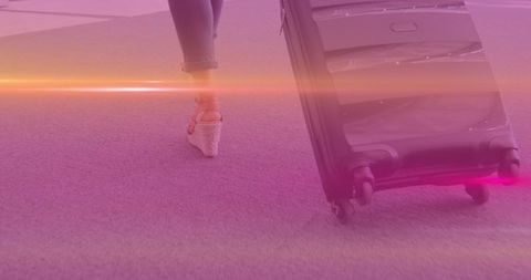 Woman wheeling suitcase on walk to work day with purple hues