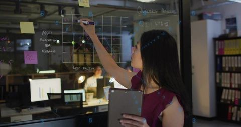 Businesswoman Examining Analytics on Glass Board in Modern Office