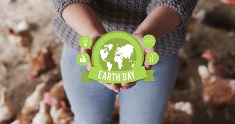 Holding earth day badge in chicken coop promoting sustainable farming and eco agriculture