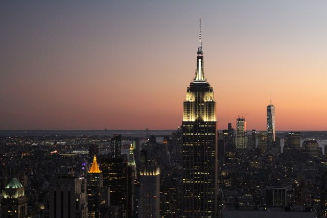 Captured during dusk, this photo provides a breathtaking view of New York City's skyline, prominently featuring the illuminated Empire State Building. Perfect for travel websites, urban-themed articles, wallpapers, or promotional materials showcasing the beauty of Manhattan.