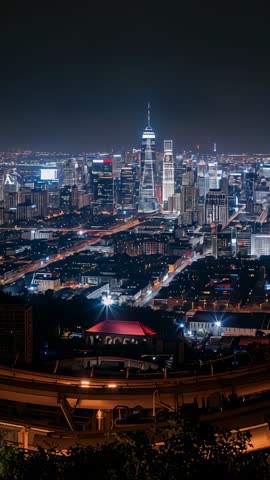 Hilltop vertical video showcasing illuminated tower and glowing highway light trails at night