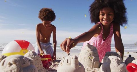Siblings crafting sandcastles at sunny beach