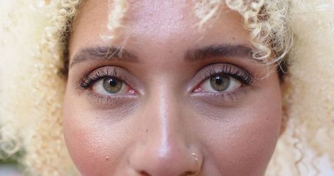 Close-up of young woman with blonde curls and nose ring