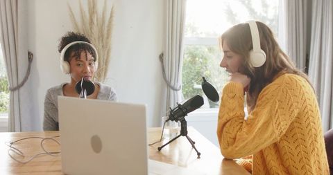 Cozy sunlit home podcast recording with diverse female cohosts using laptop and mics