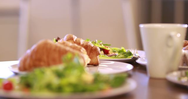 A close-up view of a breakfast table set with a croissant sandwich and a fresh salad, with copy space. The focus on the meal suggests a healthy and appetizing start to the day.