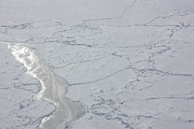 Aerial view of icy landscape in the Bellingshausen Sea with sunlight reflecting on cracked ice. Great for illustrating climate change, polar regions, extreme environments, and NASA's research on Earth's polar ice through Operation IceBridge.
