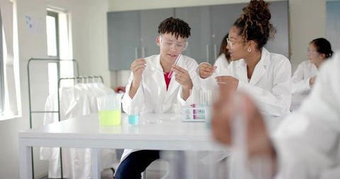 High school students conducting colorful chemistry experiments in collaborative STEM lab
