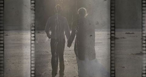 Couple holding hands on misty beach with filmstrip overlay