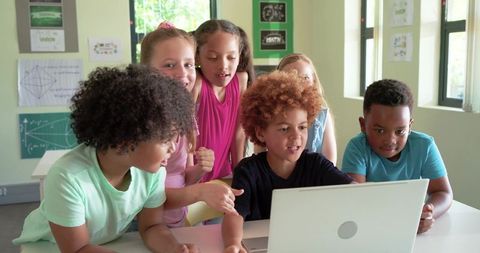 Diverse group of students collaborating on laptop in classroom, coding and learning