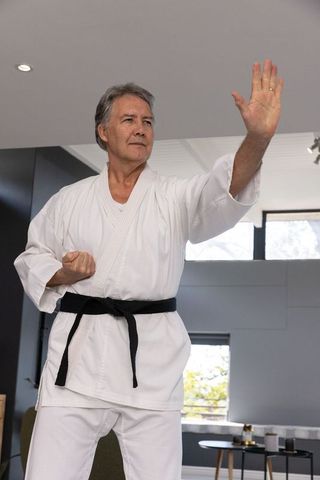 Senior Man Practicing Karate Block in Modern Room