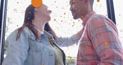 Two women leaning close at glass door with orange speckle overlay sharing tender moment