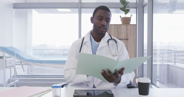 Focused Male Doctor Reviewing Patient Files in Modern Office - Download Free Stock Images Pikwizard.com