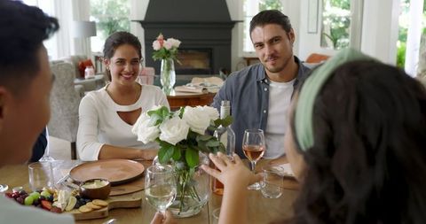 Friends Gathering Around Dining Table with Wine and Flowers
