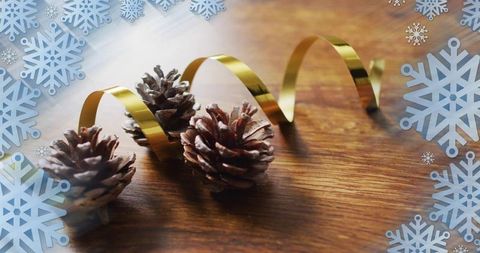 Rustic holiday pinecones with gold ribbon and snowflake overlay on wooden tabletop