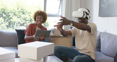 Couple testing VR headset during unboxing while using tablet in sunlit living room