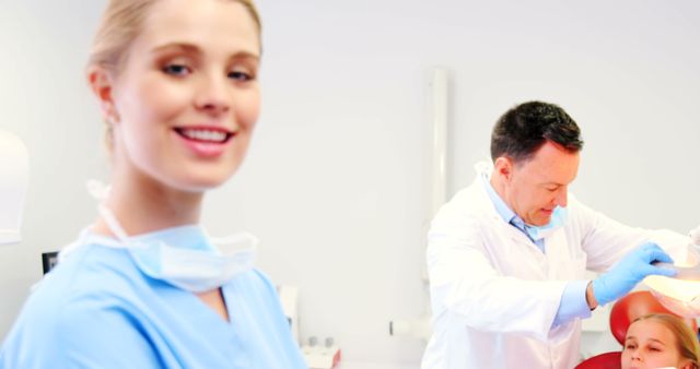 Smiling Dentist with Colleague Treating Patient in Dental Clinic - Download Free Stock Images Pikwizard.com