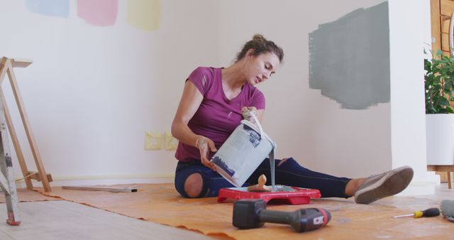 Woman Renovating Room with Paint Sits on Floor Pouring Paint - Download Free Stock Images Pikwizard.com