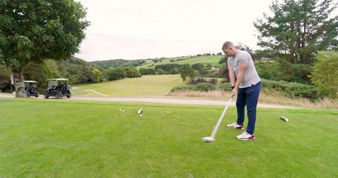 Golfer Preparing Swing on Scenic Course with Carts