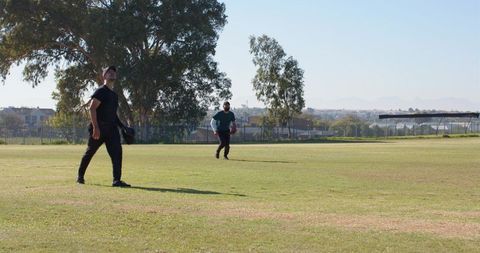 Outdoor baseball practice two male players in sportswear catching ball on sunny field