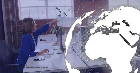 Woman in blue blazer pointing at print on divider in collaborative modern office, globe overlay
