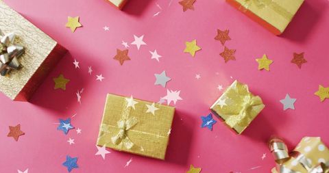 Festive gift boxes on pink with glittering star confetti
