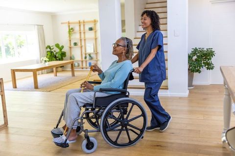 Caring Nurse Assisting Senior Woman in Wheelchair Indoors