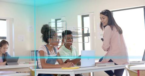 Teacher Guiding Teen Students Collaborating on Laptop and Tablet in Bright Modern Classroom