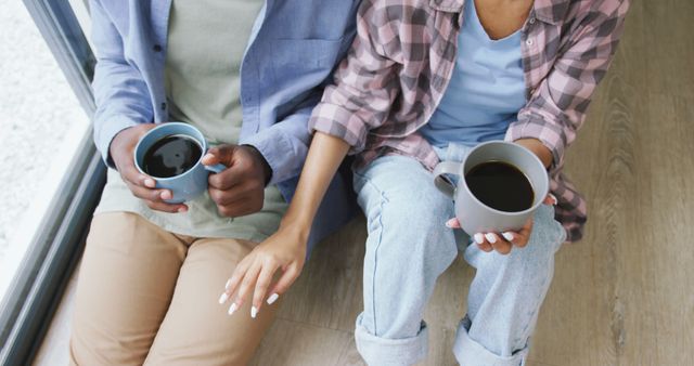 Image of midsection of african american couple drinking coffee and talking at home. love, relationship, togetherness and spending quality time at home.