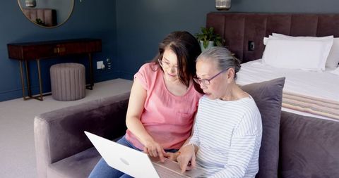 Mother and Daughter Using Laptop Together at Home in Bedroom