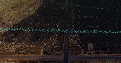 Aerial intersection crossing arid landscape with teal data overlay and coordinate grid