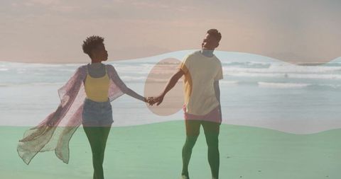 Romantic couple strolling hand in hand along ocean shoreline