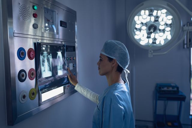 This visual portrays a female surgeon in a modern operating room, focusing on examining an x-ray. The details highlight high-tech medical equipment and the expertise of healthcare professionals in a hospital environment. Suitable for use in medical blogs, healthcare websites, educational materials, and marketing campaigns related to medical care and services.