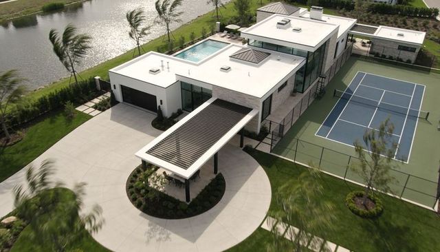 Luxury modern waterfront estate featuring rooftop pool, tennis court and porte-cochere