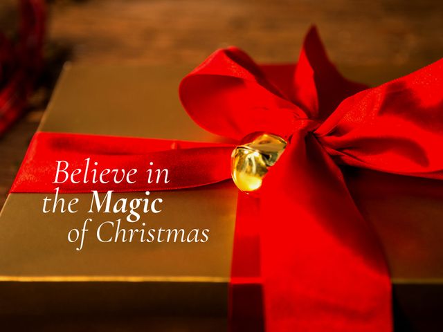 This image showcases a beautifully wrapped Christmas gift with a large red bow overlaid with text 'Believe in the Magic of Christmas.' Ideal for holiday greeting cards, social media posts, festive advertisements, and seasonal promotional materials to evoke the joy and magic of Christmas.