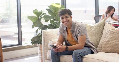 Young Man Relaxing with Smartphone in Communal Lounge