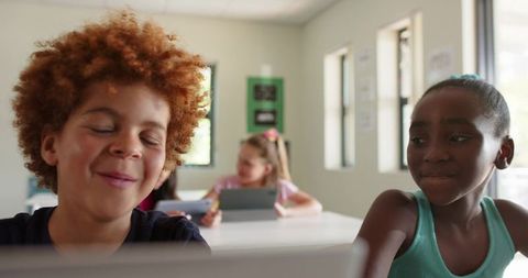 Diverse Preteen Classmates Collaborating with Tablets and Laptop in Bright Classroom