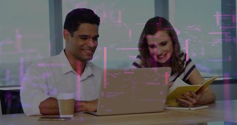 Smiling coworkers collaborating on laptop in modern office with city skyline and notebook