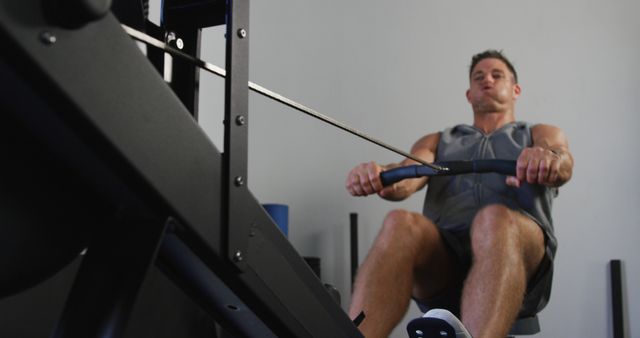 Man exercising on rowing machine in gym, focused workout - Download Free Stock Photos Pikwizard.com