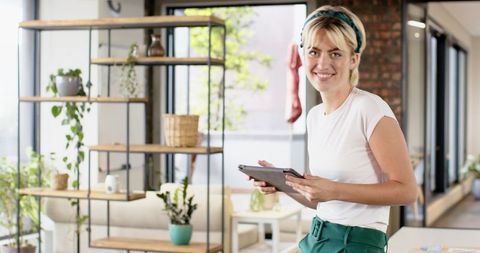 Woman Smiling with Tablet in Modern Living Room with Indoor Plants