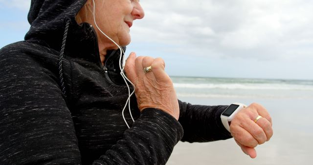 Senior Woman Exercising on Beach with Smartwatch and Earphones - Download Free Stock Images Pikwizard.com